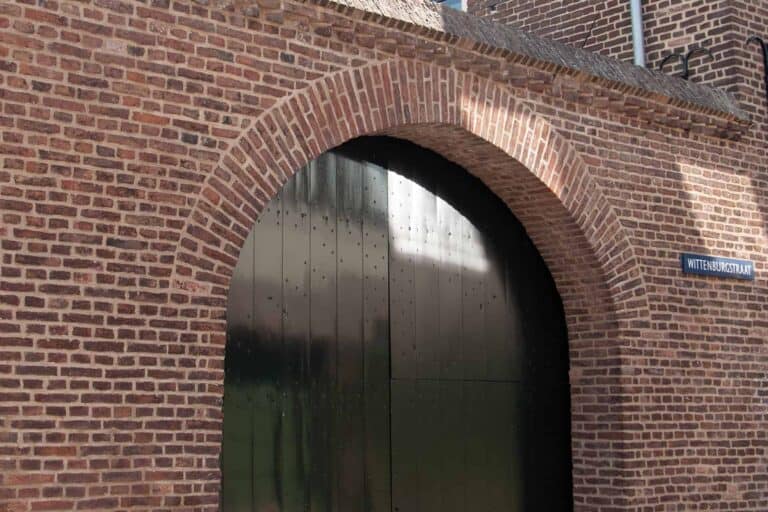 Oude bakstenen poort met groen geschilderde deur.