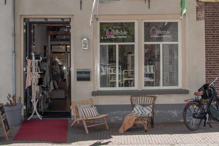 Ingang woonwinkel met stoelen en fiets voor de deur.