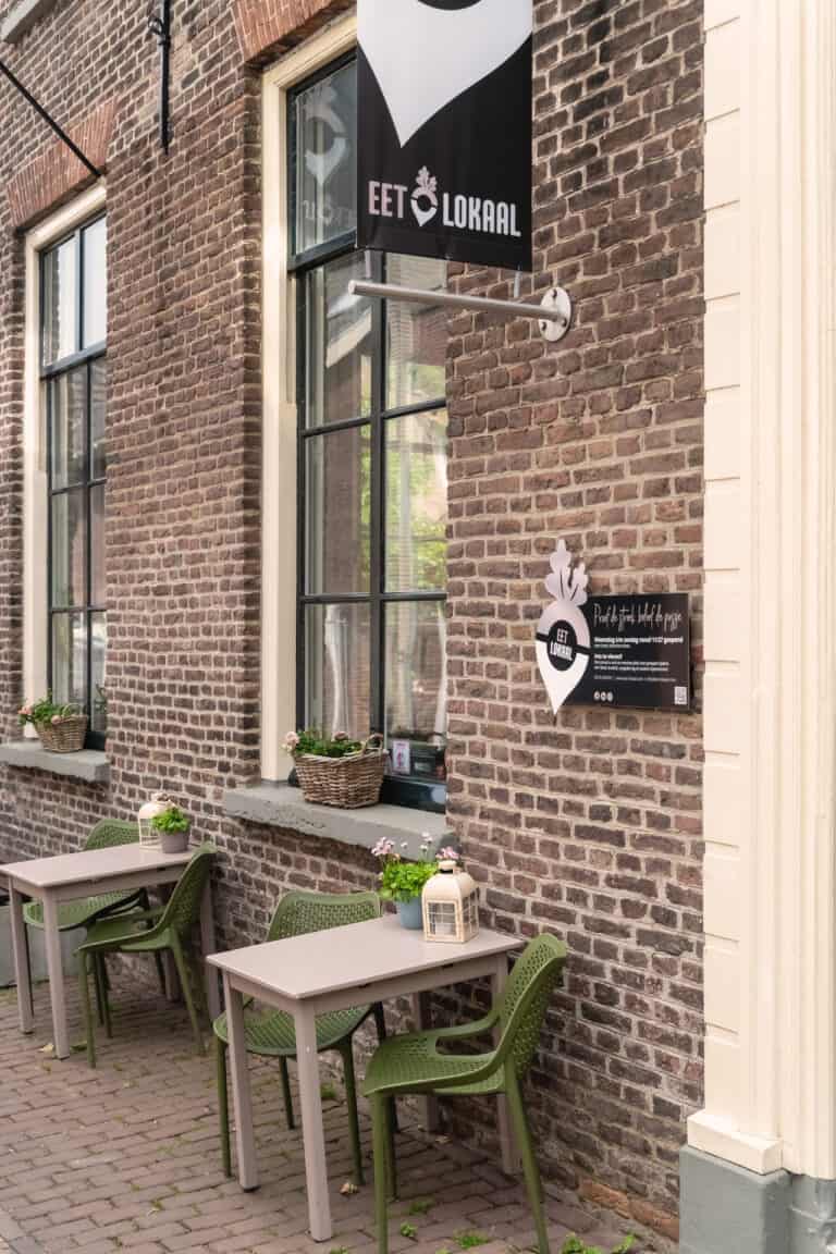 Buitentafels bij restaurant met bakstenen muur.