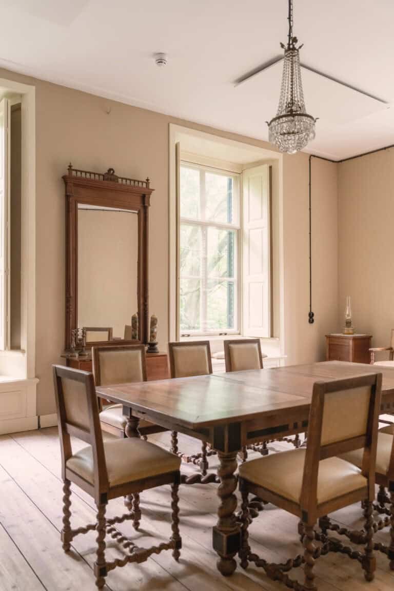 Oude houten eettafel in klassieke kamer met kroonluchter.